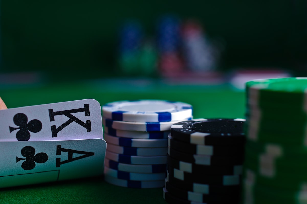 Tangan pemain memegang kartu di meja poker dengan tumpukan chip